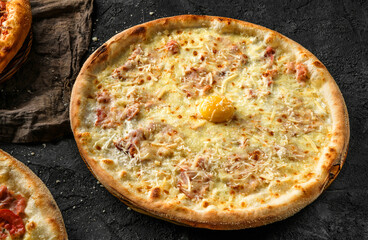 Pizza Margherita with prosciutto, cheese parmesan and yolk on stone black background. Fast food lunch for picnic company, top view