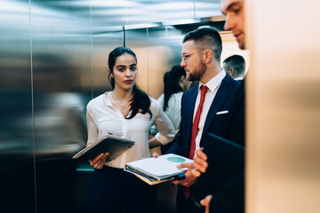 Group of coworkers in office standing in elevator