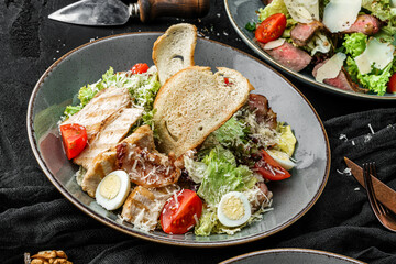 Chicken salad with eggs, tomatoes, green leaves, and parmesan served with croutons on dark background. Healthy food, clean eating, dieting, top view