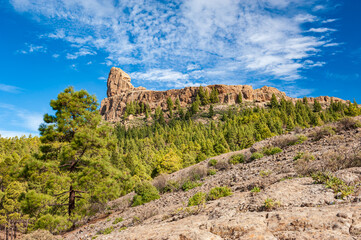 Roque Nublo, symbolic natural monument of Gran Canaria, Canary Islands. Summer sunny day with blue skies and moon and cloud sky. Emblematic volcanic rock formations in mountains of Gran Canaria Spain.