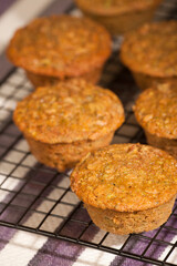 Zucchini muffins cooling on a wire rack above a striped tea towel.