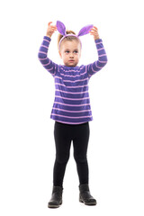 Adorable girl child looking away touching Easter bunny hat ears with uncertainty. Full body isolated on white background