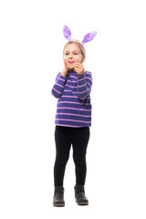 Cute young girl celebrating Easter with bunny ears with anticipation excited expression. Full body isolated on white background