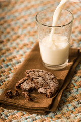 Snack of a homemade chocolate sugar cookie, with milk being poured into a glass.