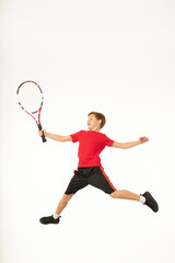 Fototapeta na wymiar Adorable boy with tennis racket jumping in studio