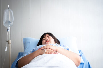 Blurred soft images of Asian fat woman patients, lying in patient's bed with alone, to people health care and diabetes concept. This picture focused on hands