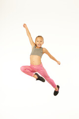 Cute female child in sportswear jumping in studio