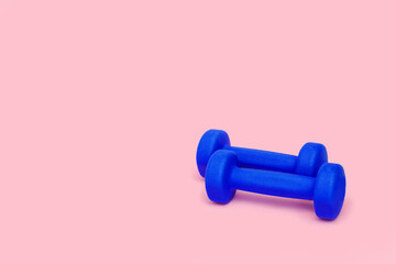 Two bright blue dumbbells isolated on pink background. Healthy lifestyle. Sport equipment. Fitness concept. Copy space for design