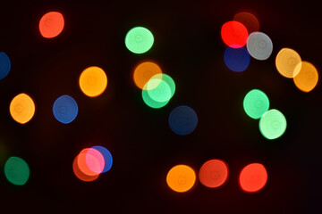 Colorful bokeh circles on a dark background. Abstract and blurred image. Bright christmas lights