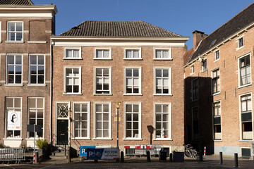 Square mansion with large window panes in historic medieval exterior facades of Hanseatic city center against a clear blue sky. 