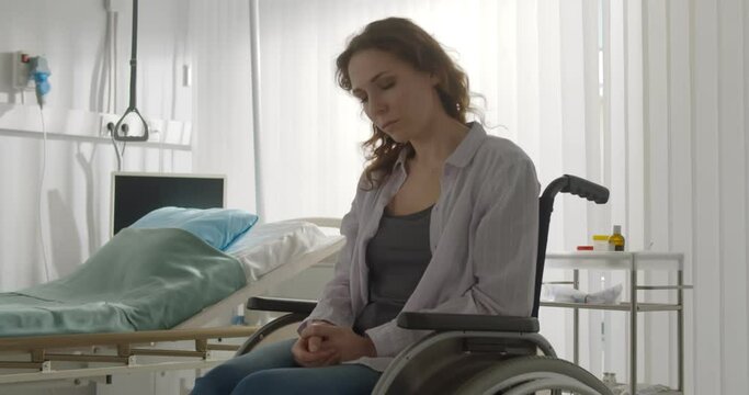 Woman patient feeling depressed and frustrated sitting in wheelchair in hospital.