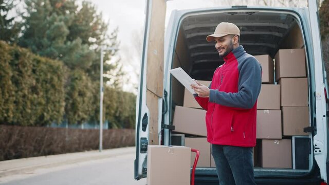Young man using tablet to view information about the parcel. Delivering the package. High quality 4k footage