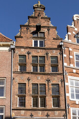 Fototapeta na wymiar Frontal view of a historic medieval mansion exterior facade in Hanseatic city center Zutphen, The Netherlands, against a clear blue sky with typical gable shape. Europe tourism destination.
