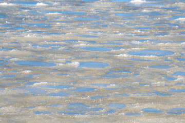 Frozen crystallized water and ice, on the surface of the ocean, with a slight skim of frozen water. The frosty ice has been broken with cool cracks of transparent frost along with the ice shifts. 