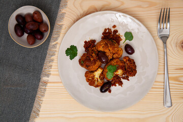 Cauliflower with tomato sauce cooked salad with olives. Moroccan cuisine.