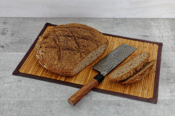 Sliced cut bread loaf with knife made from modern Damascus steel made by Japanese artisan placed on...