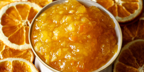 Orange marmalade in bowl. Portion of orange fruit jam with dried orange slices.