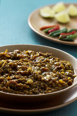Whole mung bean curry plates with fresh ingredients: garlic,  limes and chili on wooden table. Close-up view;