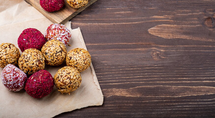 Energy balls with different flavors on a wooden board. Free space on the right. Wooden background.