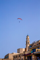 Fototapeta na wymiar Tel Aviv-Jaffo, Israel - March 15, 2021: Panoramic view of Jaffa's ancient port and paraglider flying with paramotor on air