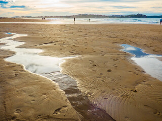 Charcos de bajamar en la arena dorada de una playa de la bahía de Santander, España