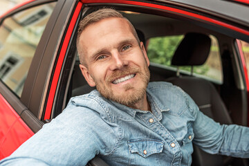 Man with a beard driving a car.