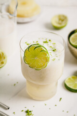 fresh lime juice, lime zest and pineapple. Served in a glass and garnished with a slice of lime.