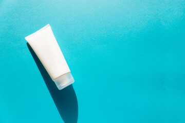 White bottle of cream or cleansing product for skin and face hygiene on blue background.