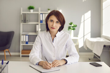 Female doctor writes notes during a video conference or listening to medical online training. Concept of online training for doctors to gain new skills, professionalism and modern technology.