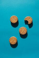 Cookies with chocolate filling on blue background. One bitten cookie. Sunlight and hard shadows