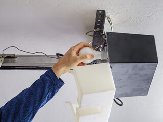 Man replacing light bulb in residential home overhead garage door opener.