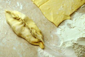 dough and a small pie on the table with flour close-up