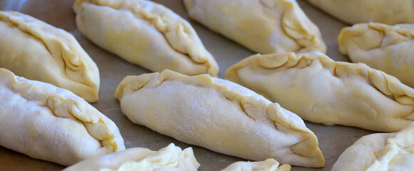 raw small pies on a baking sheet for food background