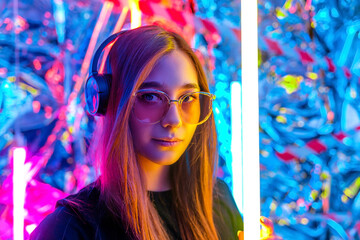a young, attractive woman wearing headphones listens to music in the neon night light. girl DJ....