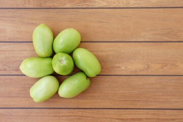 Green tomatoes on wooden background.