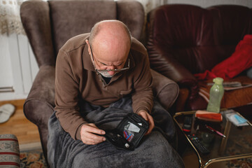 Senior men with glucometer checking blood sugar level at home