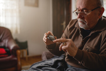 Obraz na płótnie Canvas Senior men with glucometer checking blood sugar level at home