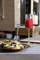 avocado sandwich and strawberry juice with a wooden cabin in background signifying healthy...