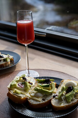 avocado sandwich and strawberry juice with a wooden cabin in background signifying healthy breakfast during camping