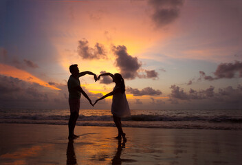 Fototapeta premium The image of silhouette of two people in love at sunset in Thailand