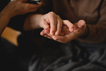 Close up off woman checking blood sugar her diabetic husband
