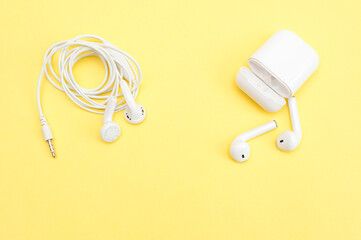 White wireless headphones and earphones on a yellow background. Concept 