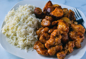 orange chicken with a side of white rice and potatoes