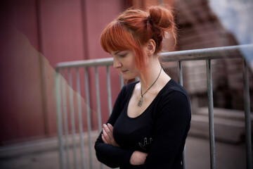 portrait girl with red hair looks down on the street