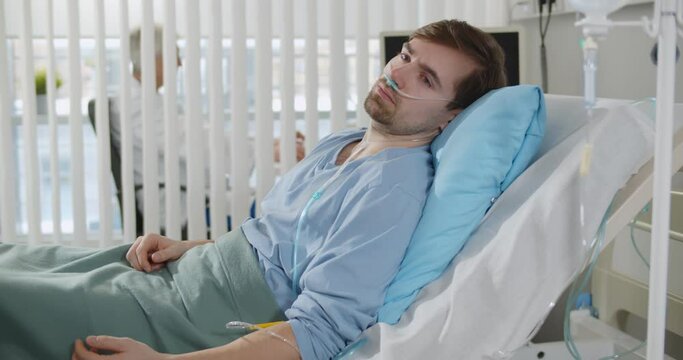 Seriously ill young man lying on bed in hospital ward