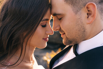 close-up profile of newlyweds in nature. Beautiful makeup, the length of curly dark hair of the bride.