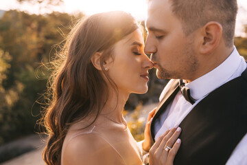 gentle beautiful bride, the groom touch the tip of the girl's nose at sunset.