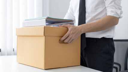 Businessman wearing a black suit raises a brown cardboard box from the office, Businessmen pack...
