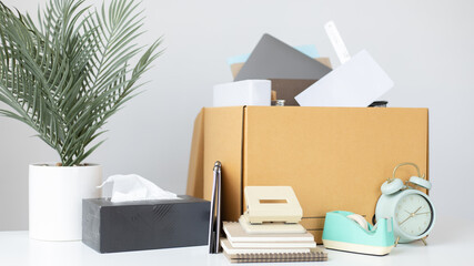 Brown cardboard box inside contains office equipment and resignation envelopes, Relocating or changing jobs or getting promoted, Resignation letter.