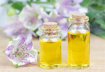 Glass bottles aroma oil and flowers on wooden table. Spa Treatment